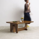 Vintage Midcentury teak wood coffee table with Art Deco influences, with a vase and small items on a plain background