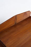Close-up of a warm brown wooden furniture piece showing the grain, a vertical seam, and a light-colored wall background.