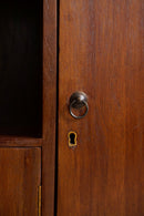 Close-up of a warm brown wooden cabinet door with a round metal ring pull handle and a matching keyhole cutout.