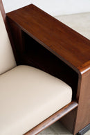 Close-up of an Art Deco sofa with a warm brown wood frame and cream-colored upholstered seat and back cushion.