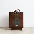 A converted Art Deco speaker cabinet with brass accents and a glass door, shown against a plain white wall and concrete floor.