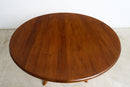 A round vubtage wooden dining table with a glossy warm brown finish and visible wood grain, photographed indoors against a plain white wall and light floor.