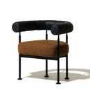 Modern occasional chair with curved backrest, black metal frame and brown boucle cushion on a white background