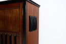 A close-up of a dark brown wooden cabinet or chest with black trim and decorative black side panels, shown against a plain white background.