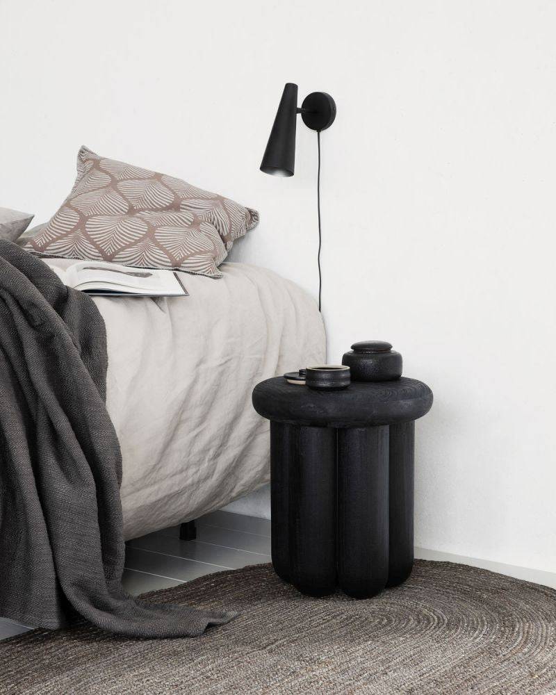 A zoom out shot of the Phant side table in a bedroom.
